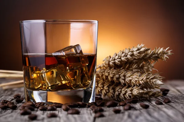 Glazen voor whisky met ijs en tarwe op een houten tafel. — Stockfoto