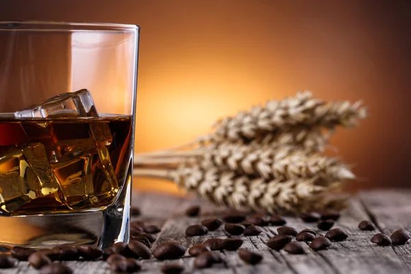 Kieliszek whisky z lodem i pszenicy na drewnianym stołem. — Zdjęcie stockowe