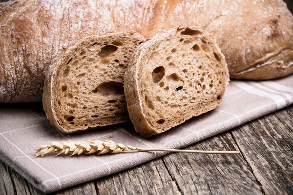 Tasty bread with wheat on wooden background. — Stock Photo, Image