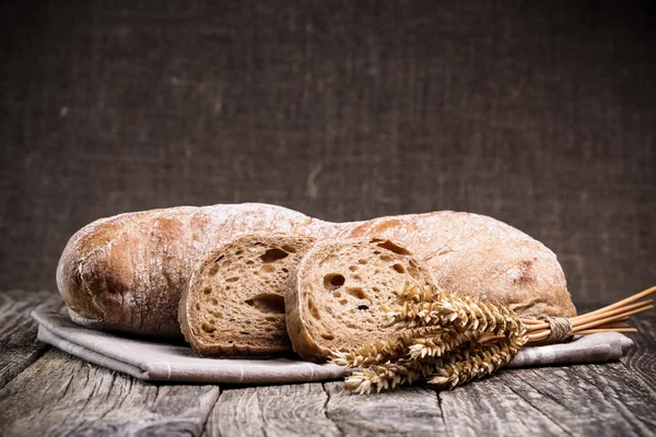 Pane saporito con grano su sfondo di legno . — Foto Stock