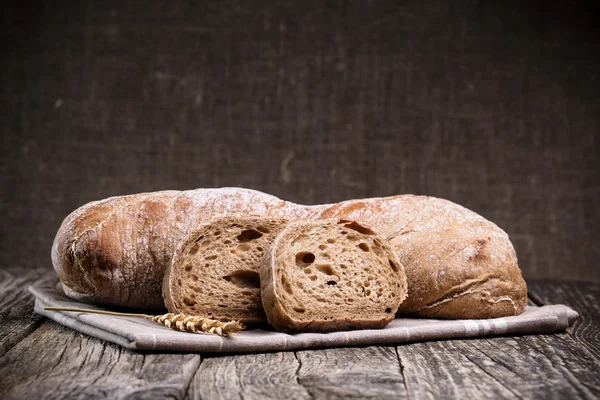 Pane saporito con grano su sfondo di legno . — Foto Stock