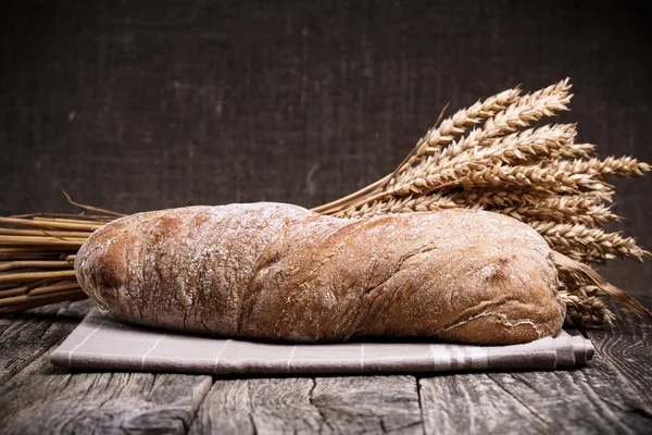 Вкусный хлеб с пшеницей на деревянном фоне . — стоковое фото