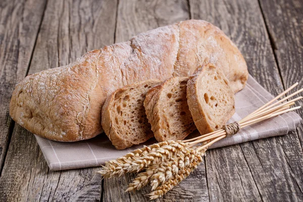 Pain savoureux avec du blé sur fond de bois . — Photo