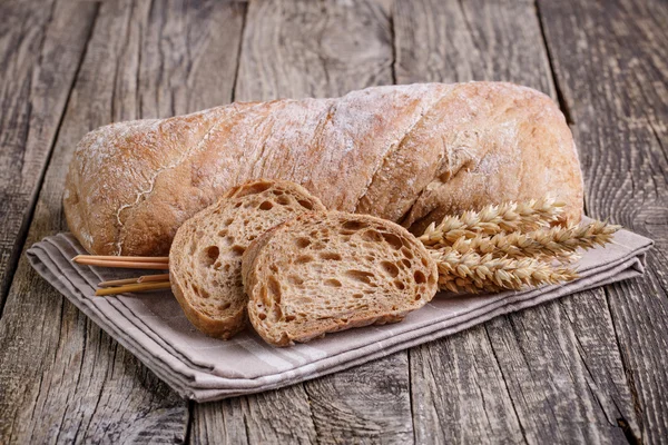 Tasty bread with wheat on wooden background. — Stock Photo, Image