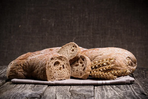 Pane saporito con grano su sfondo di legno . — Foto Stock