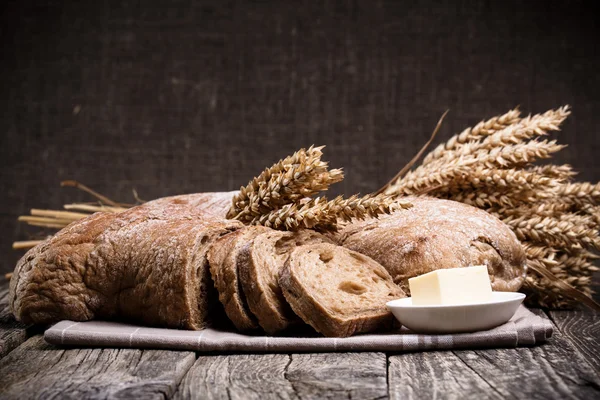 Tasty bread with wheat on wooden background. — Stock Photo, Image