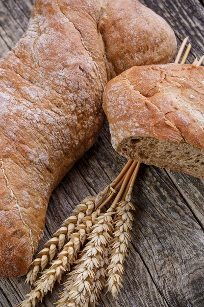 Pão saboroso com trigo no fundo de madeira . — Fotografia de Stock