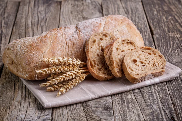 Tasty bread with wheat on wooden background. — Stock Photo, Image