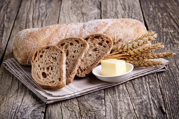 Tasty bread with wheat on wooden background. — Stock Photo, Image