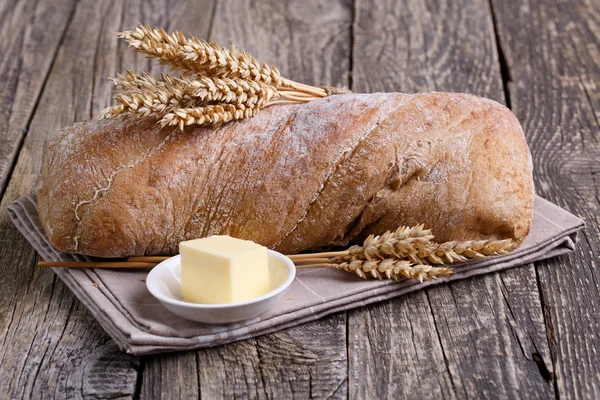 Tasty bread with wheat on wooden background. — Stock Photo, Image