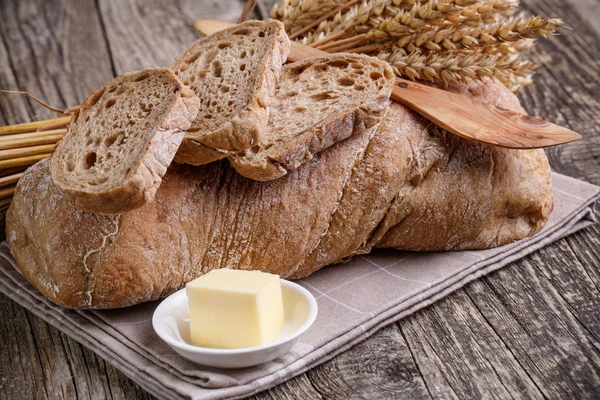 Tasty bread with wheat on wooden background. — Stock Photo, Image