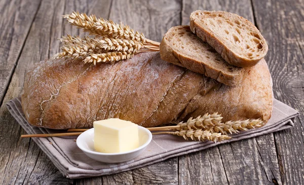 Tasty bread with wheat on wooden background. — Stock Photo, Image