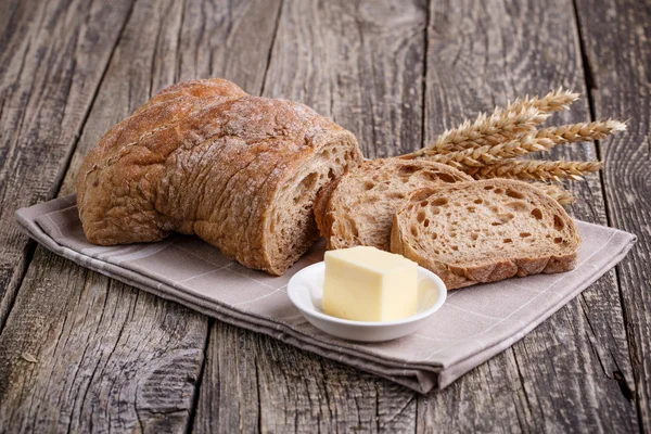 Tasty bread with wheat on wooden background. — Stock Photo, Image