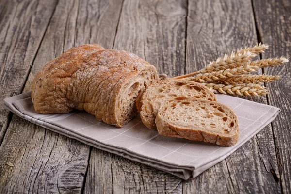 Pain savoureux avec du blé sur fond de bois . — Photo