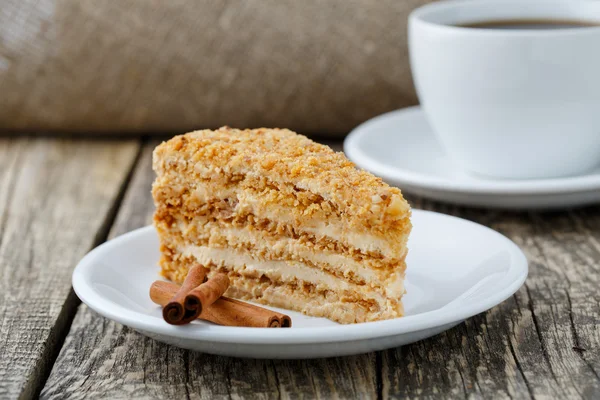 Вкусный медовый торт с чашкой кофе на деревянном фоне . — стоковое фото