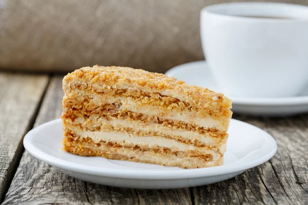 Вкусный медовый торт с чашкой кофе на деревянном фоне . — стоковое фото