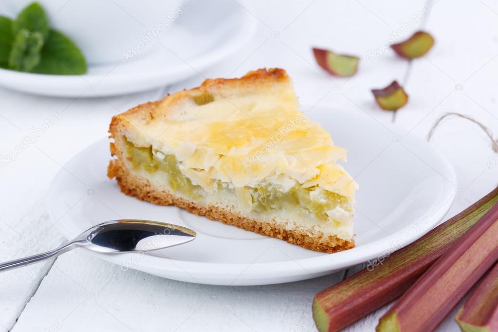 Tasty slice of rhubarb pie on white wooden table.