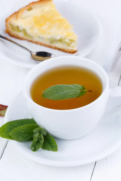 Thé à la menthe avec tranche de tarte à la rhubarbe sur table en bois . — Photo