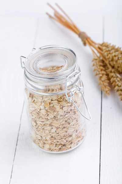 Los copos de avena en frasco de vidrio y trigo . — Foto de Stock