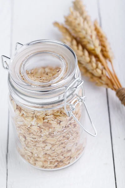 Los copos de avena en frasco de vidrio y trigo . —  Fotos de Stock