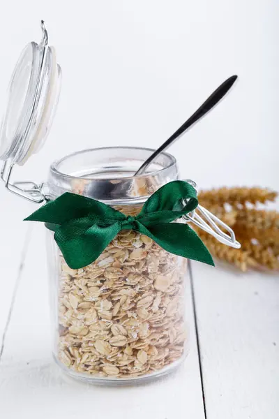 The oat flakes in glass jar and green ribbon. — Stock Photo, Image