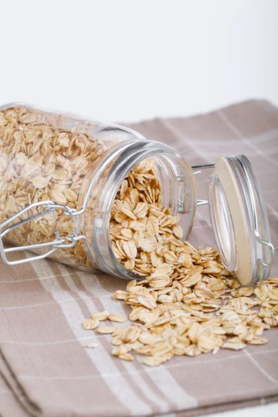 The oat flakes in glass jar on brown towel. — Stock Photo, Image