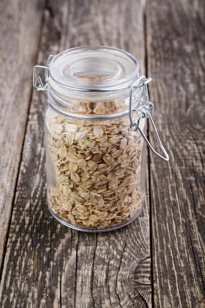 The oat flakes in glass jar on wooden background. — Stock Photo, Image