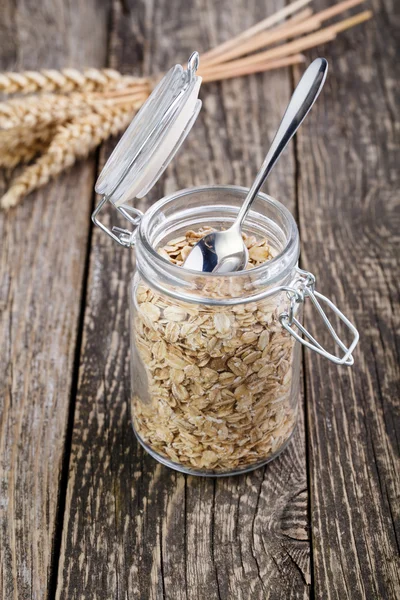 Haferflocken im Glas und Weizen auf Holztisch. — Stockfoto