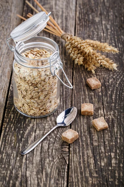 Los copos de avena en frasco con azúcar morena y cuchara . —  Fotos de Stock