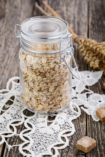 The oat flakes in jar with sugar on lace napkin. — Stock Photo, Image