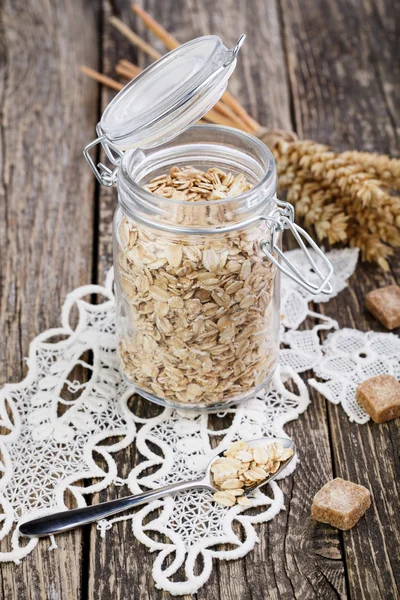 The oat flakes in jar with sugar on lace napkin. — Stock Photo, Image