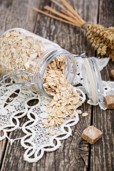 Oat flakes spilled out from jar and brown sugar. — Stock Photo, Image