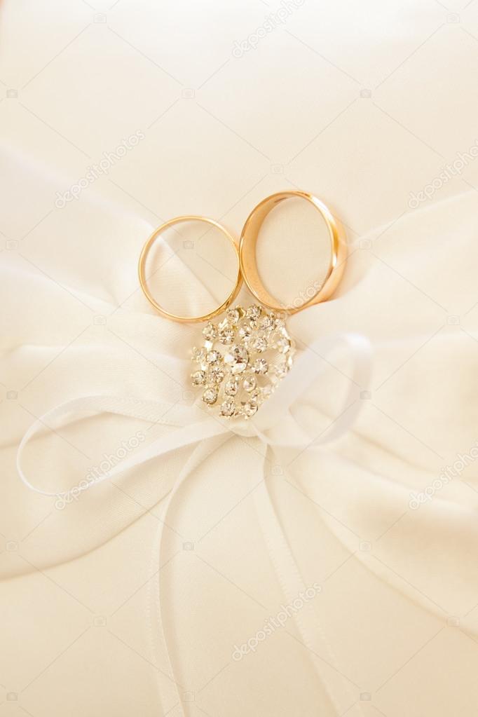 Gold wedding rings on a pillow.