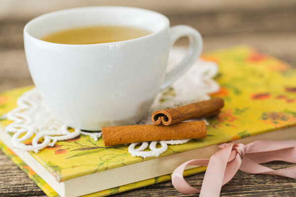 Белая чашка ромашкового чая и книга на столе
.