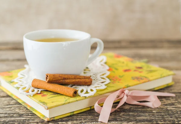 Weiße Tasse Kamillentee und Buch auf dem Tisch. — Stockfoto