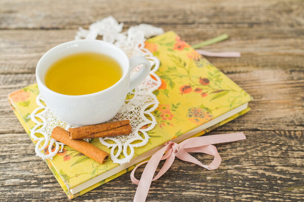 Белая чашка ромашкового чая и книга на столе
.