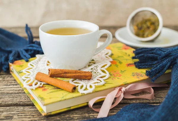 Weiße Tasse Kamillentee und Buch auf dem Tisch. — Stockfoto