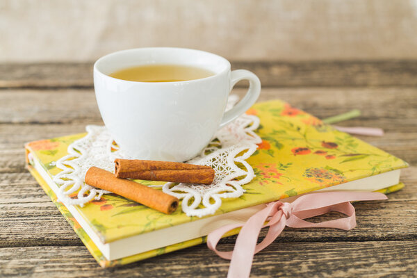 Белая чашка ромашкового чая и книга на столе
.