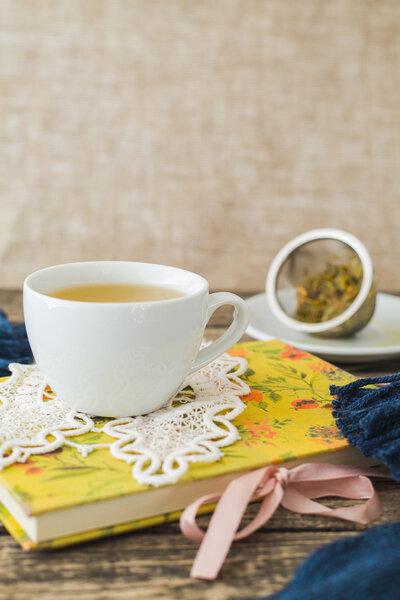 Белая чашка ромашкового чая и книга на столе
.