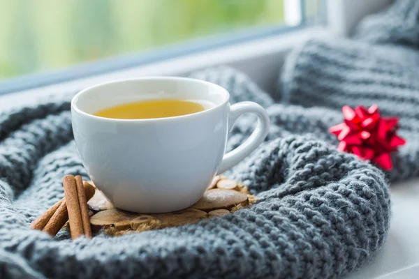 Tasse blanche de thé à la camomille avec foulard gris sur le rebord de la fenêtre . — Photo