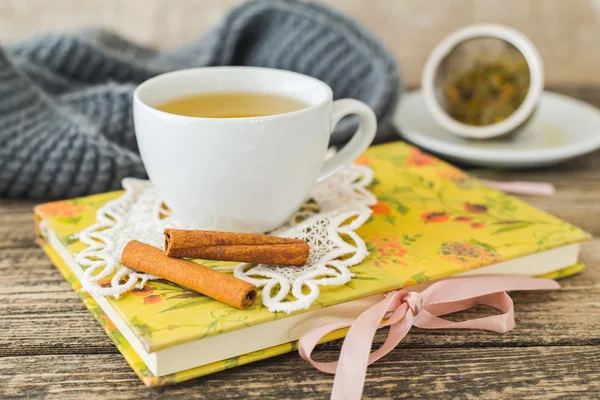 Weiße Tasse Kamillentee und Buch auf dem Tisch. — Stockfoto