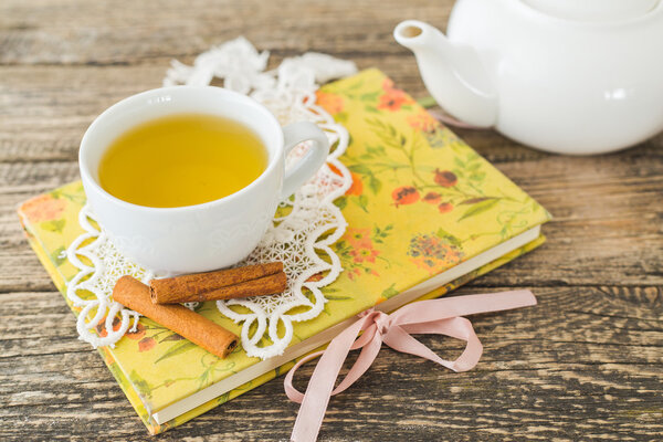 Белая чашка ромашкового чая и книга на столе
.