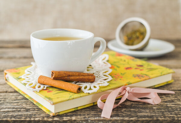 Белая чашка ромашкового чая и книга на столе
.