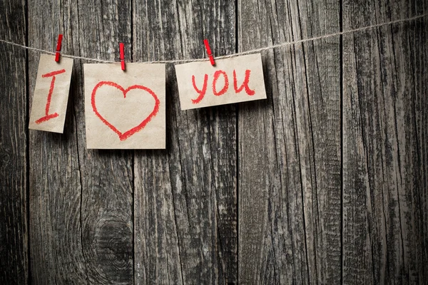 Napsaná slova miluji vás a srdce na dřevěné pozadí. — Stock fotografie