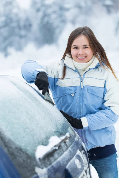 美丽的年轻女子，从她的车除雪. 免版税图库照片