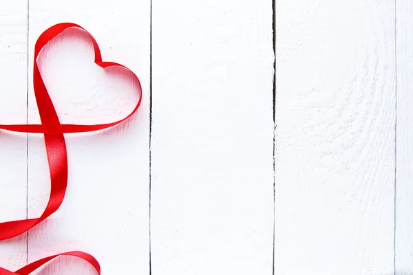 Cinta roja en forma de corazón sobre mesa blanca . — Foto de Stock