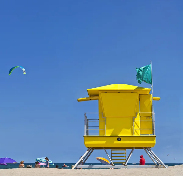 Yellow Life Guard Tower at the beach with people, kite surfer and blue sky