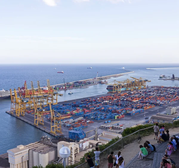 Algunas personas descansan en la colina Montjuic con vistas a la parte industrial del Puerto de Barcelona — Foto de Stock