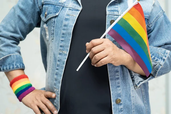 亚洲女人穿着蓝色牛仔夹克或斜纹棉布衬衫 手持彩虹彩旗 象征男女同性恋 双性恋 变性者自豪月 每年六月庆祝男女同性恋者 双性恋者 变性者 人权社会日 — 图库照片