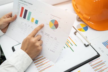 Modern ofis, finans ve iş konseptinde grafik grafik grafiği ve hesap makinesiyle çalışan ve finansal raporları analiz eden Asyalı muhasebeci.